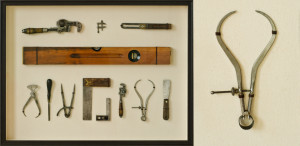 Vintage carpenter hand tools with leather fasteners in shadow box